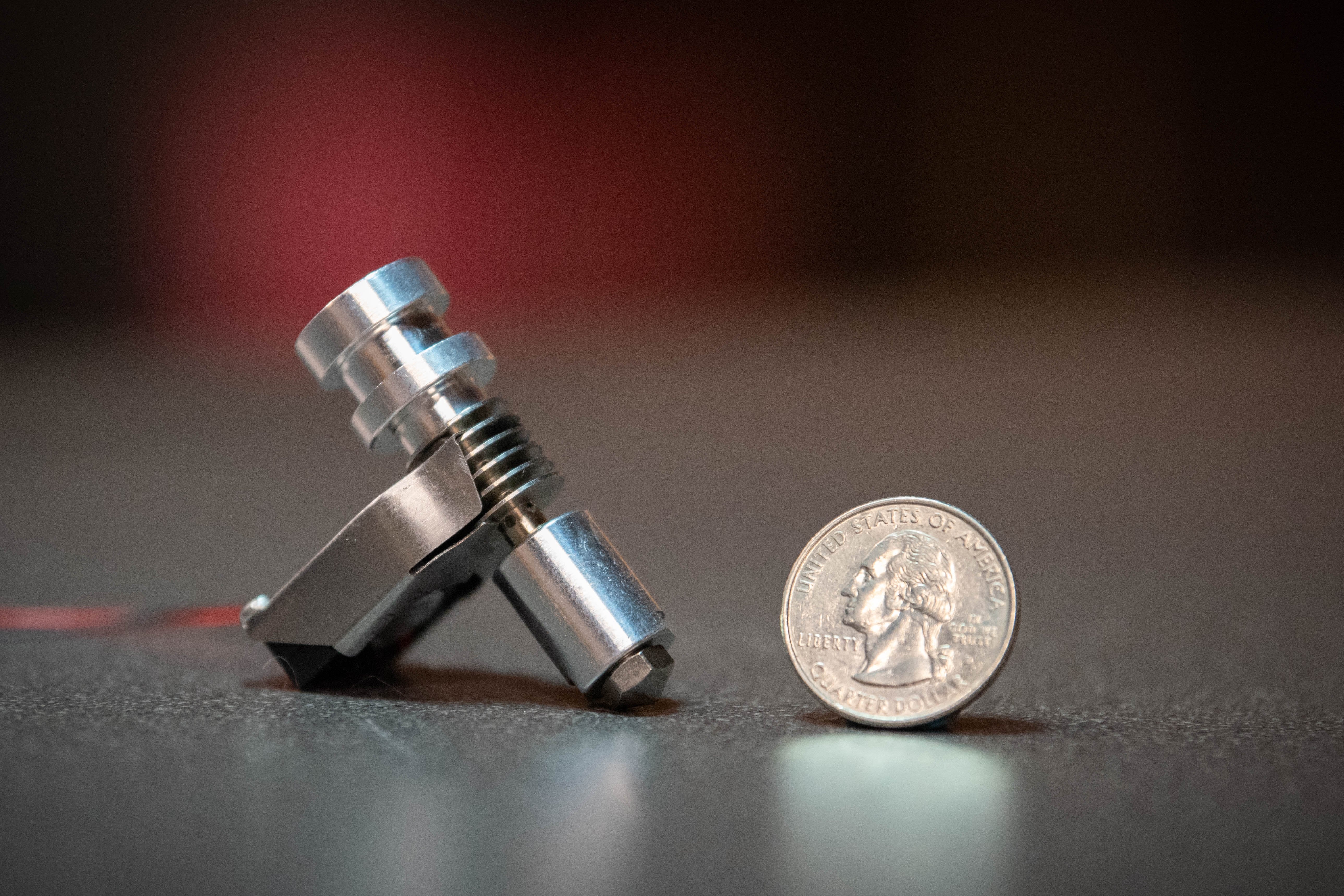 Assembled Pico Hybrid 3D printer hot end by metaform with sheet metal fan shroud attached. Hot end is sitting on a table next to a quarter.